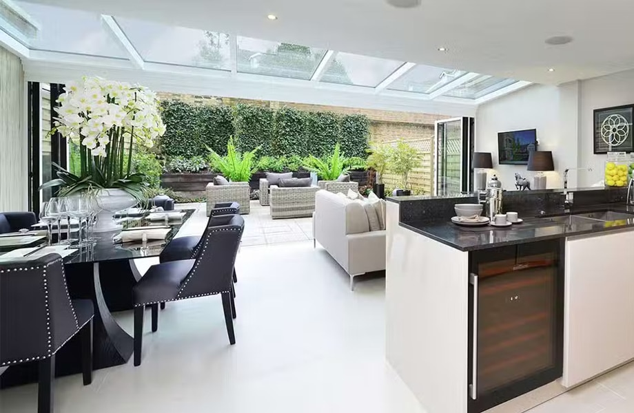 Glass lean-to roof system with aluminium framing in contemporary open-plan kitchen and dining space overlooking garden