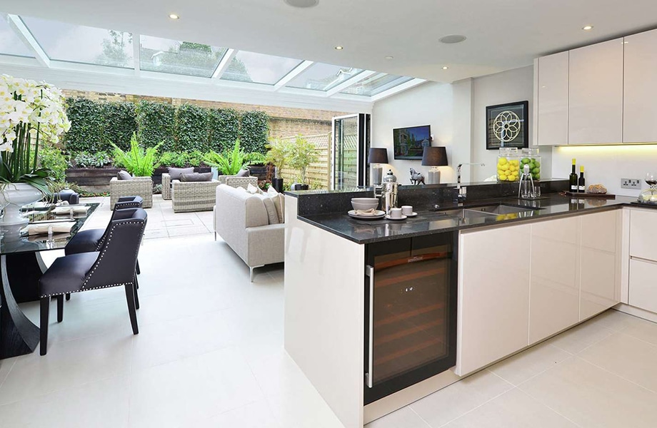 Modern open-plan kitchen and living space with aluminium bifold doors opening to landscaped garden, demonstrating residential glazing systems for housebuilders.